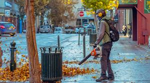 man using leaf blower on street